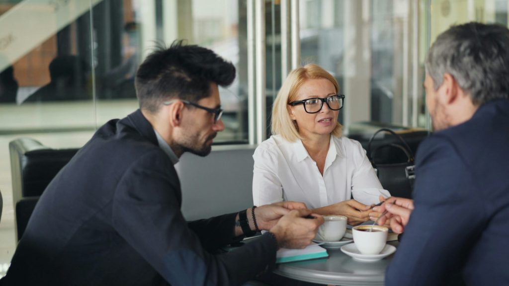 a group of people sitting around a table talking