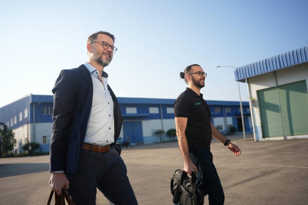Two businessmen walking outside an industrial building.